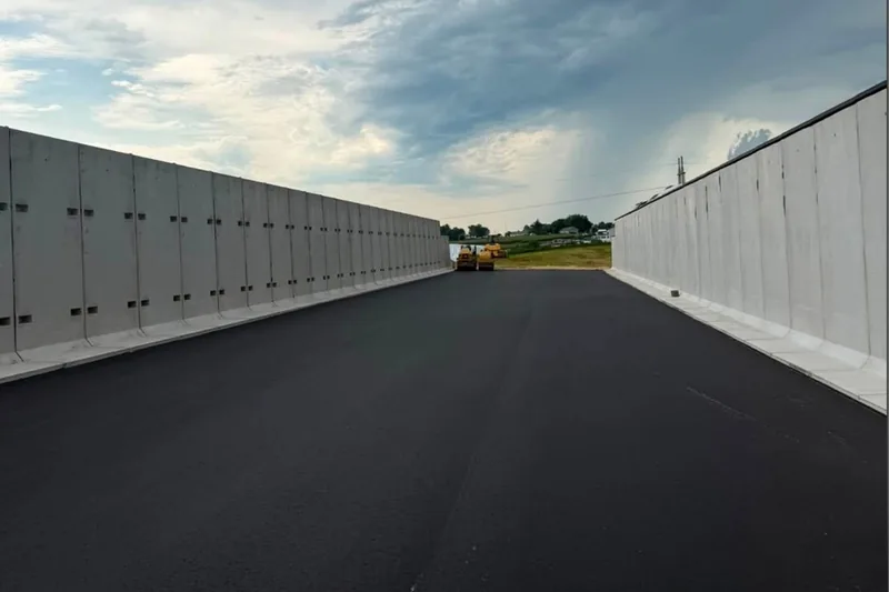 Fresh asphalt floor laid between tall concrete feed bunker walls
