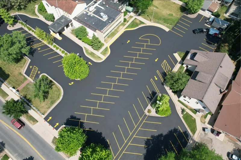 Aerial view of a freshly paved and striped parking lot with yellow stalls and arrows