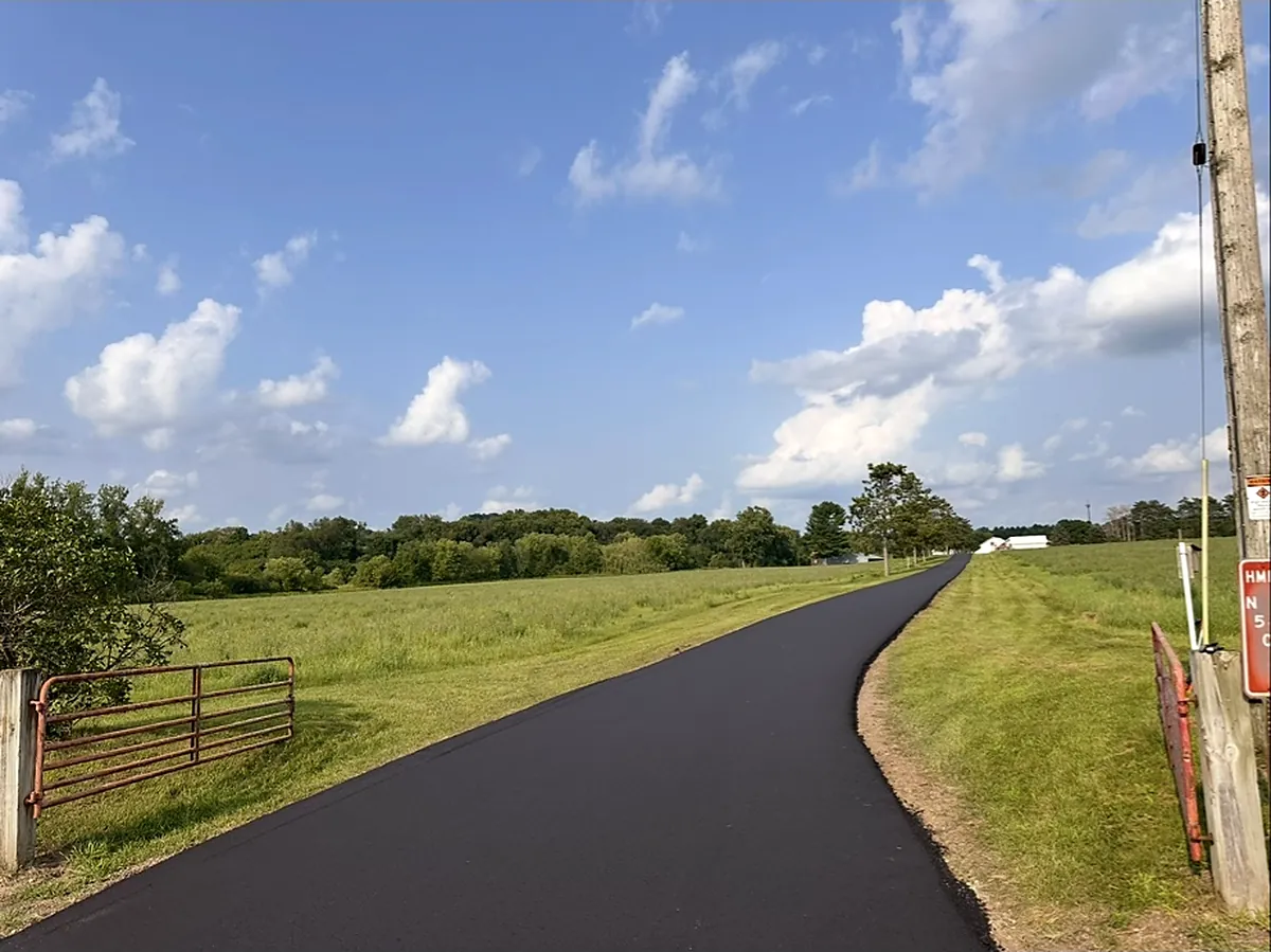 New drive curving past the gate toward the field