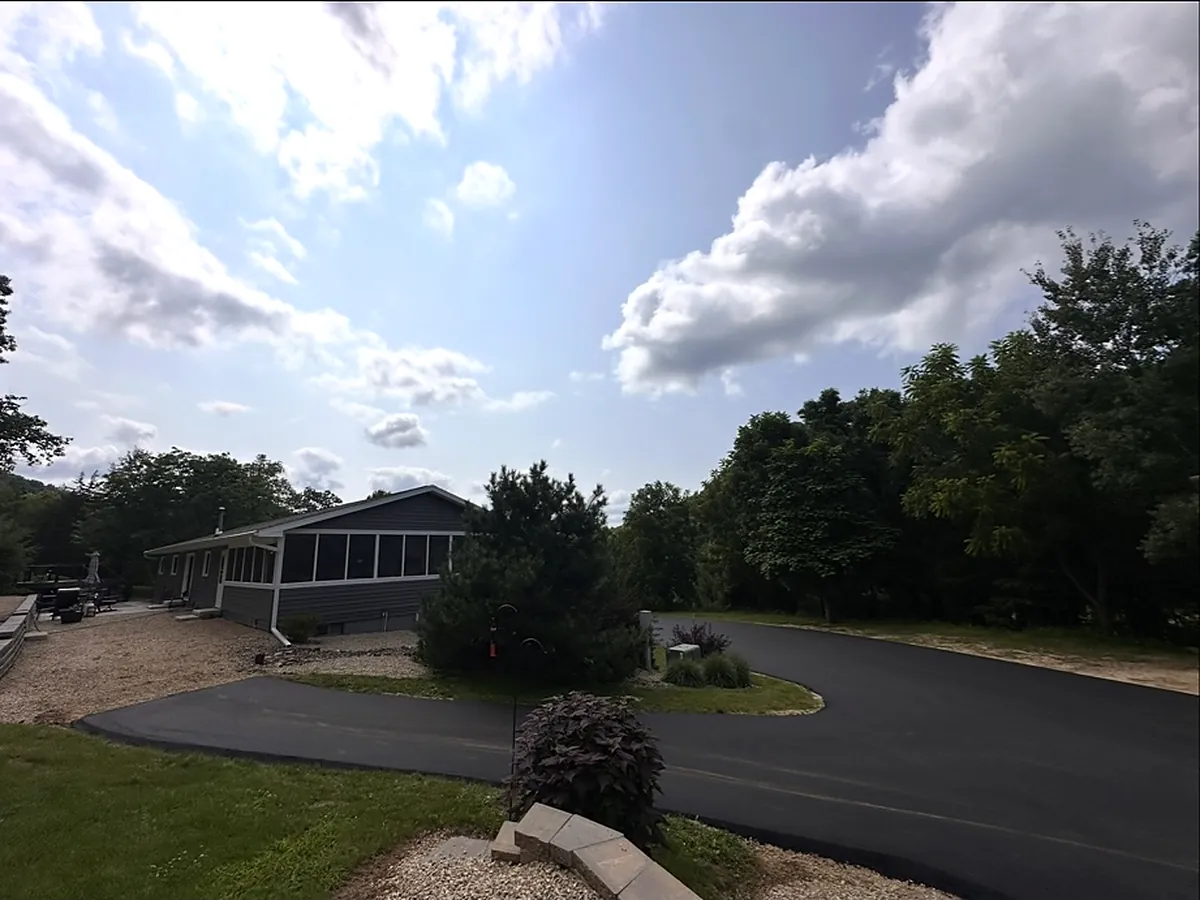 Wide drive turning in front of a ranch home with a screened porch