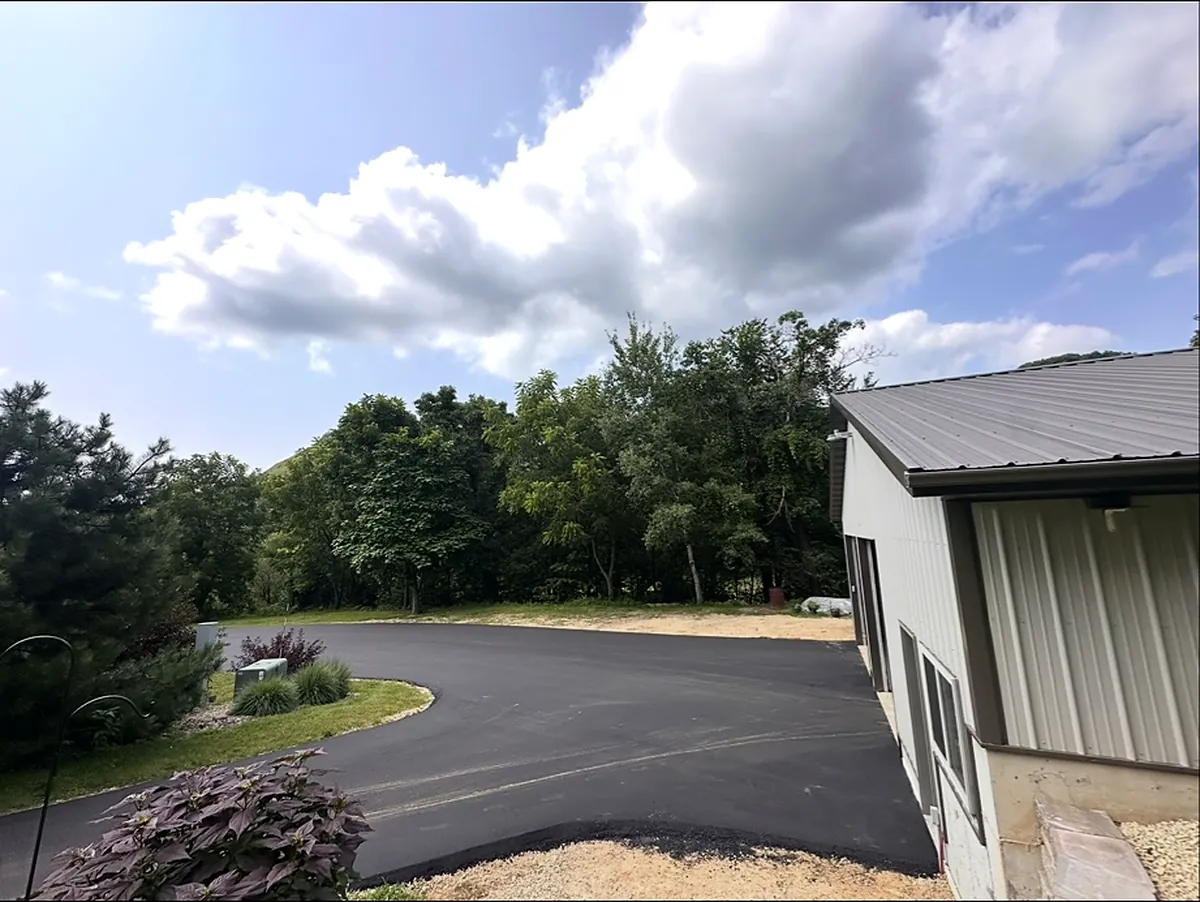 Drive wrapping around a gray steel shop building