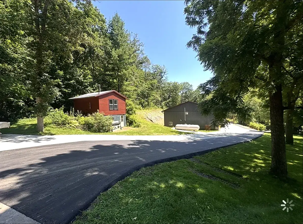 Drive turning into the yard between a red barn and outbuilding