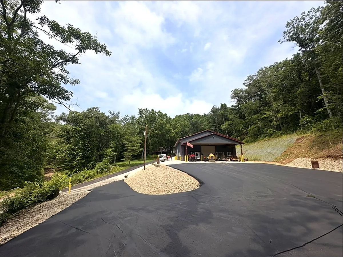 Wide asphalt turnaround in front of a hillside home