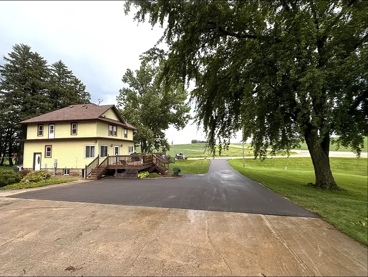 Drive running alongside a yellow house with a deck