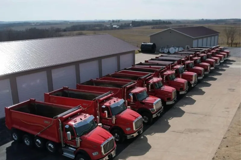 Row of red Strub dump trucks lined up along the shop at the home yard